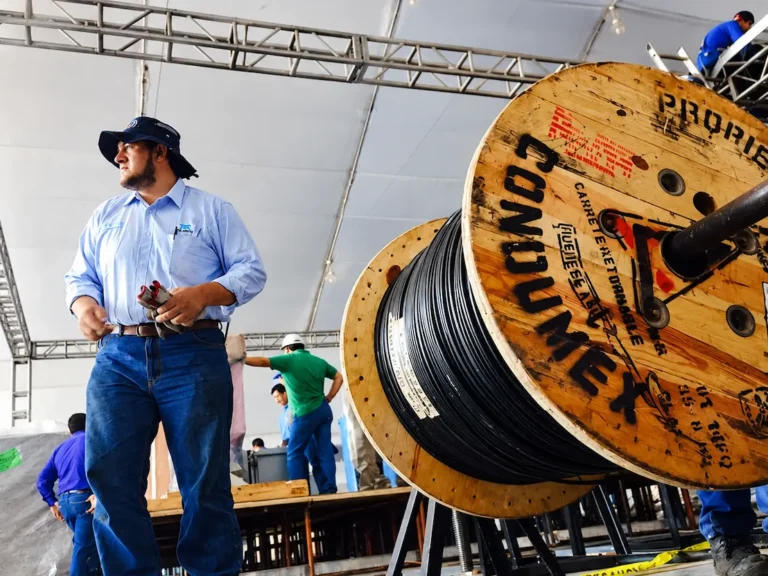 Trabajadores de telecomunicaciones junto a una bobina de cable Condumex durante labores de instalación de infraestructura para redes de telefonía e Internet.